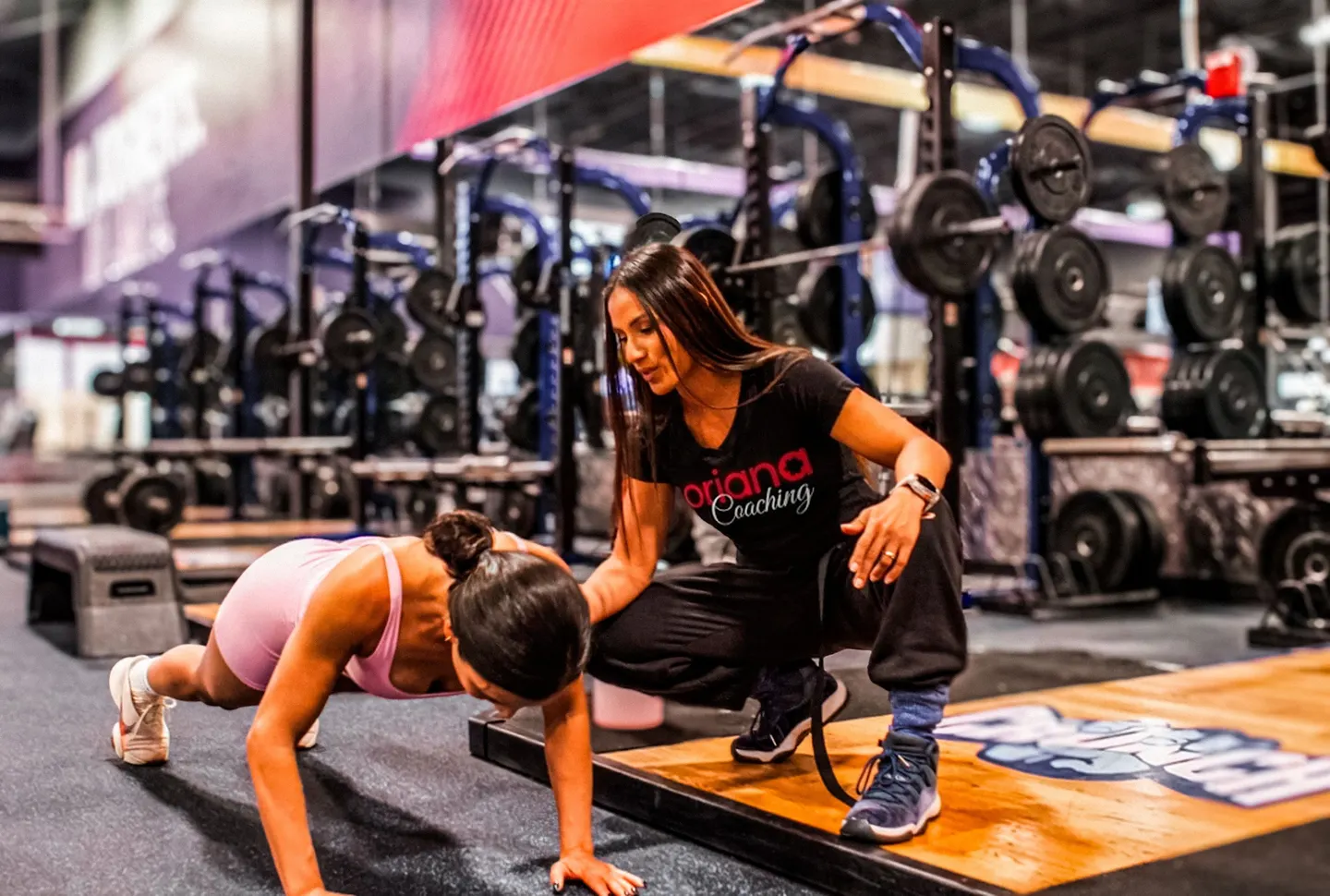 Oriana corrigiendo la técnica de una clienta durante una plancha en el gym